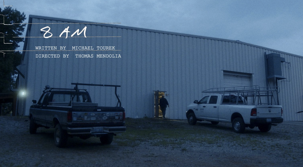 Two trucks outside white warehouse building with "8 AM" title in top corner